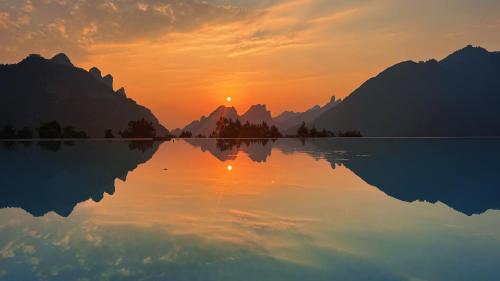 a reflection of the sun in the water at sunset at XMAN Sunrise Peaks Resort--Free Pick-up in Zhangjiajie
