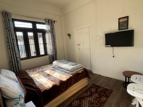 a bedroom with a bed and a tv on the wall at La Renada in Mawphlang