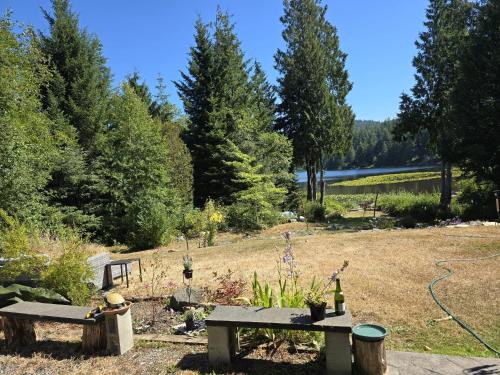 a garden with two benches and a lake in the background at Davidson Star in Sooke