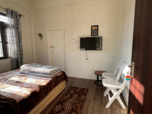 a bedroom with a bed and a tv and a chair at La Renada in Mawphlang