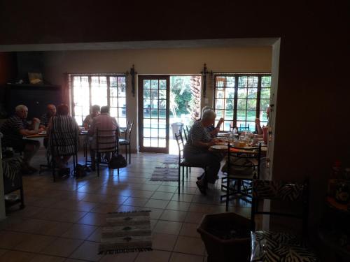 a group of people sitting at tables in a restaurant at A Cherry Lane Self Catering and B&B in Bloemfontein