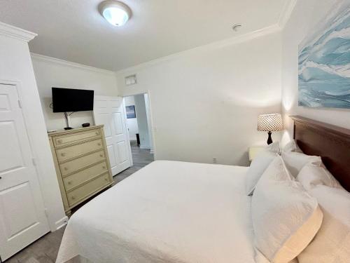 a bedroom with a bed and a tv on a dresser at Awesome Mediterranean Resort! 15 minutes to Disney in Kissimmee