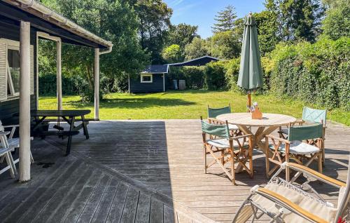 a wooden deck with a table and an umbrella at 4 Bedroom Amazing Home In Vejby in Vejby