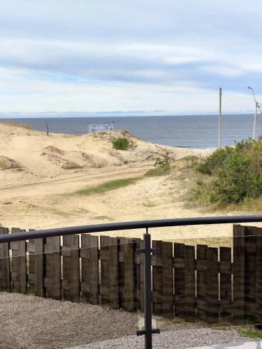 a view of a beach with a fence and the ocean at Arenas del Diablo in Punta Del Diablo