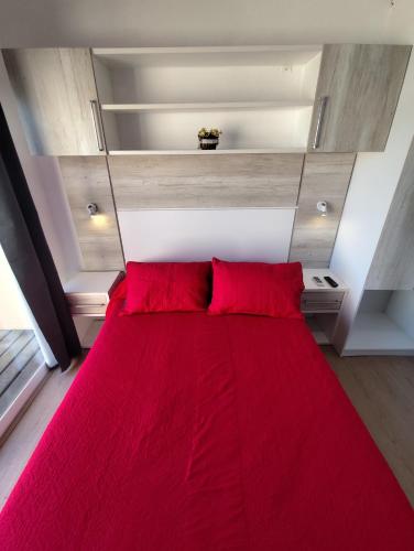 a bed with red pillows in a small room at Arenas del Diablo in Punta Del Diablo