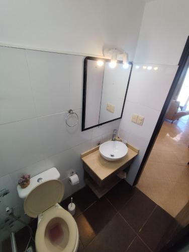 a bathroom with a toilet and a sink and a mirror at Arenas del Diablo in Punta Del Diablo