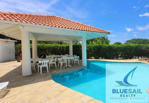 a pavilion with a table and chairs next to a swimming pool at tropicana sur apt221 in Sosúa