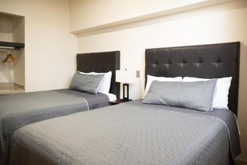 two beds sitting next to each other in a bedroom at Hotel America Centro in Los Mochis