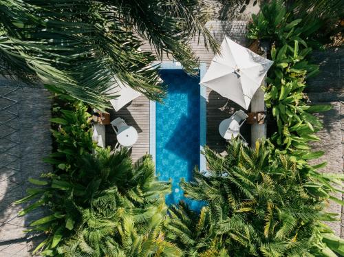 an overhead view of a swimming pool with an umbrella at Burudika Bungalows - Villas, Sauna & Bath House in Selong Belanak