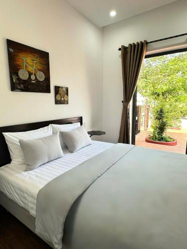 a bedroom with a large white bed and a window at Laa House in Hoi An