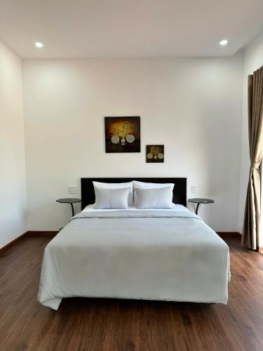 a bedroom with a large white bed with two tables at Laa House in Hoi An