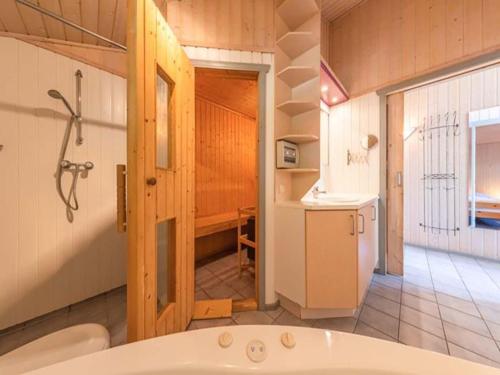 a bathroom with a tub and a sink and a refrigerator at Ferienhaus mit Sauna im Ferienpark Mirow in Granzow