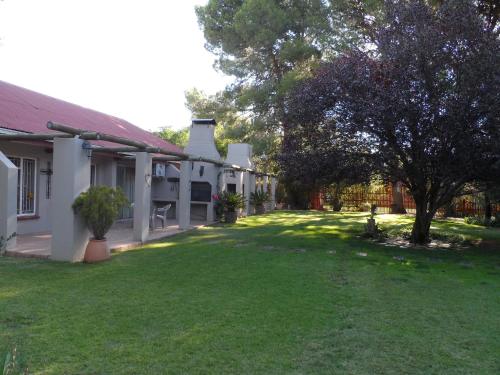 a yard next to a house with a tree at A Cherry Lane Self Catering and B&B in Bloemfontein