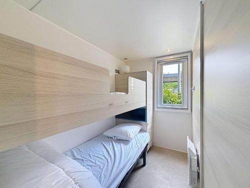 une petite chambre avec un lit et une fenêtre dans l'établissement Mobil-home moderne 3 chambres, terrasse, animaux admis - FR-1-361A-97, à Jullouville