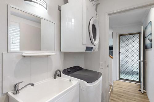 bagno bianco con lavandino e lavatrice di 6 Pelican Beach Resort a Noosaville