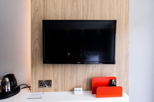 a flat screen tv hanging on a wall with a red chair at Holiday Inn Express Norwich by IHG in Norwich