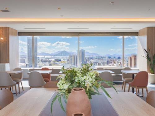 a room with a table and chairs and a large window at Mitsui Garden Hotel Hiroshima in Hiroshima