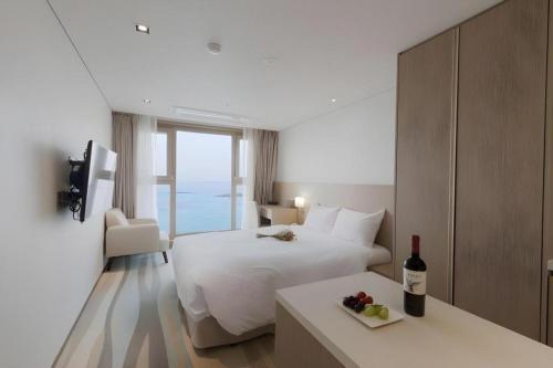 a hotel room with a bed and a bottle of wine at Ebenezer Hotel in Jeju