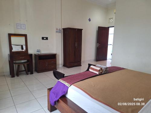 a bedroom with a bed and a vanity and a mirror at Ayuri Guesthouse in Karangasem