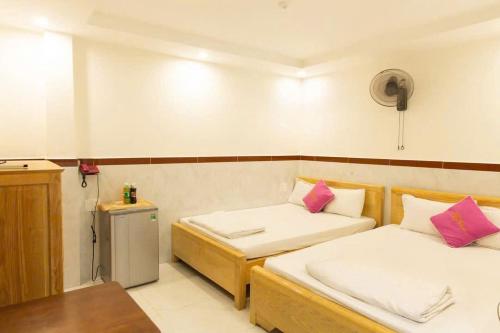 a small room with two beds and a refrigerator at Thị Thành Hotel in Vung Tau