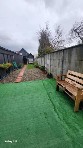 a wooden bench sitting on a green lawn at Cabaña en ambiente familiar in Valdivia
