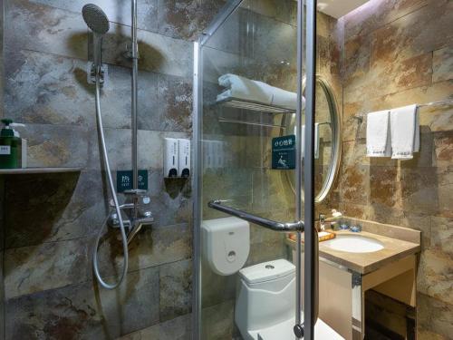 a bathroom with a shower and a toilet and a sink at Leisurely Hotel Shenzhen in Shenzhen