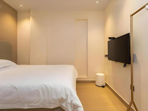 a bedroom with a bed and a flat screen tv at Leisurely Hotel Shenzhen in Shenzhen