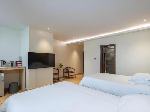 two beds in a hotel room with a tv at Leisurely Hotel Shenzhen in Shenzhen