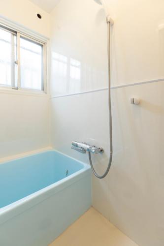 a white bathroom with a tub and a window at カトレアコーポ美野島 in Sumiyoshi
