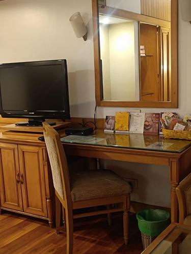 a desk with a television and a desk with a mirror at Pride Hotel Pune in Pune
