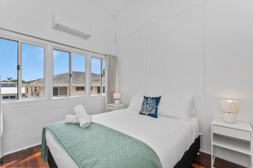 a white bedroom with a bed and a window at Townsville Suites in Townsville