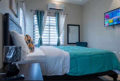 a bedroom with a bed with a blue blanket and a window at Emerald SunDara Villa Ochi in Ocho Rios