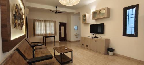 a living room with a table and a tv at La Tamara Luxury - TIE Hotels & Resorts in Pondicherry