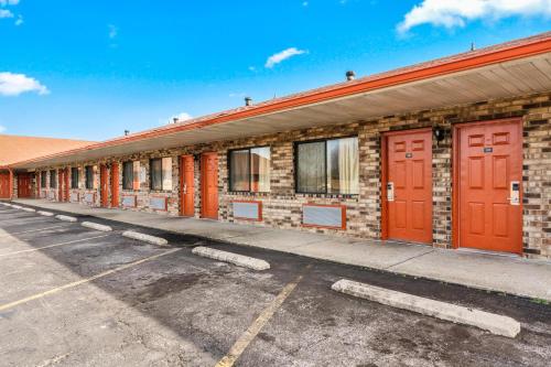 a brick building with red doors in a parking lot at Budget Host Inn by Hotel O Portland near I-65 in Portland