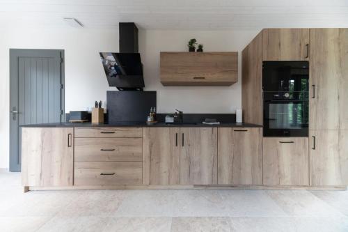 a kitchen with wooden cabinets and a black counter top at Maison Billy - Maison design et climatisée avec jardin in Billy