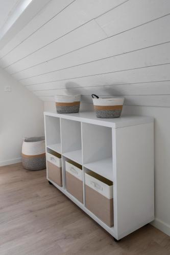 a white shelf with two baskets on it in a room at Maison Billy - Maison design et climatisée avec jardin in Billy