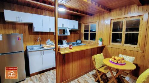 a kitchen with white cabinets and a table with a bowl of fruit at La Casa de Darío - Hospedaje y Casa de Campo en Oxapampa con Piscina in Oxapampa