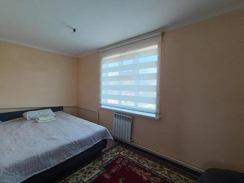 a bedroom with a bed and a window at Guest House South Wind in Pokrovka
