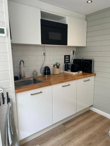 a kitchen with white cabinets and a sink and a microwave at Zandvoort Boutique Apartments in Zandvoort