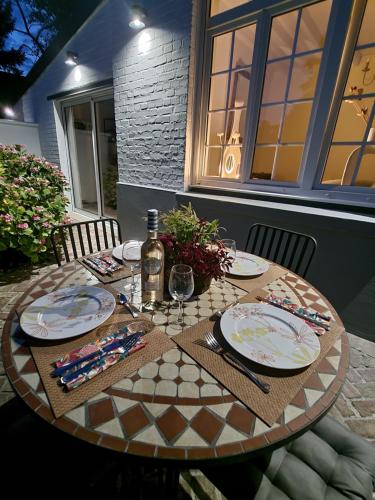 einen Tisch mit Tellern und eine Flasche Wein in der Unterkunft La petite maison blanche in Dunkerque