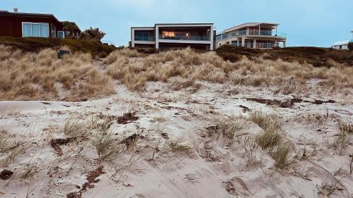 a house sitting on top of a sandy beach at Beachside Bliss in Tauranga