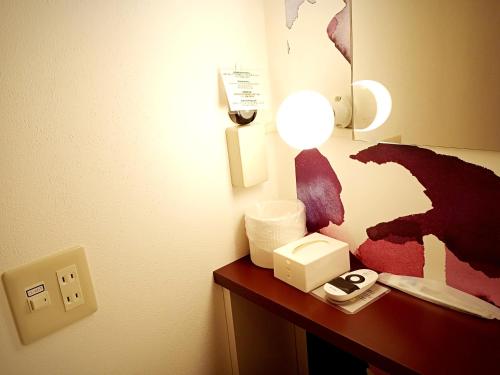 宇都宮市にある女性専用ゲストハウス-Female only Guesthouse-Travel Stay UTSUNOMIYAのデスク、電話、ランプが備わる客室です。