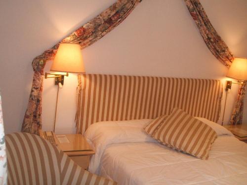 a bedroom with a bed and a lamp and a chair at El Mirador Hotel & Spa in Colonia del Sacramento
