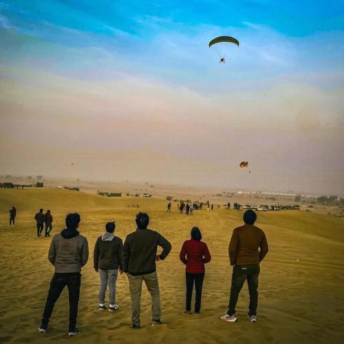 a group of people standing in a field flying kites at Sam Desert Luxury Resort in Sām