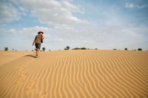 a man walking on a sand dune in the desert at Sam Desert Luxury Resort in Sām