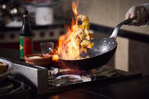 a person cooking food in a wok on a stove at Hotel Grand Kaptan - Ultra All Inclusive in Alanya