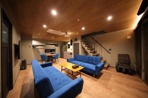 a living room with blue couches and a staircase at FUJI TIME TRAVELER Morino in Fujikawaguchiko