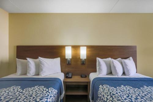 a hotel room with two beds and a wooden headboard at Days Inn by Wyndham Newark Wilmington in Newark