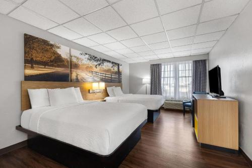 マディソンビルにあるDays Inn by Wyndham Madisonvilleのベッド2台と薄型テレビ付きのホテルの部屋