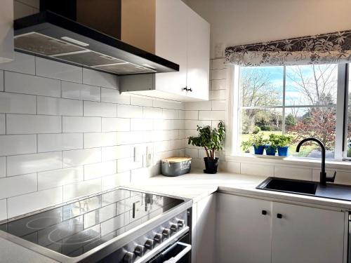 a white kitchen with a sink and a window at 64 Mandalea B&B in Ohoka